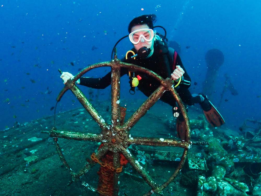 Diver holding the Boga Wreck steering wheel near Tulamben, Bali
