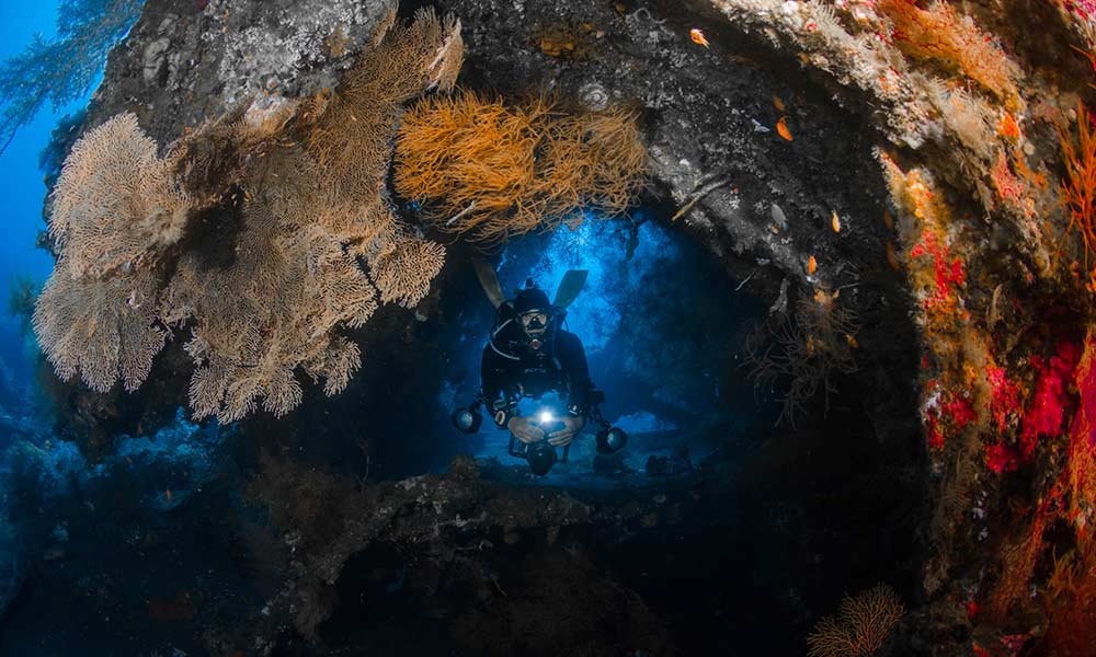 Man scuba diving inside the USAT Liberty Wreck in Tulamben Bali