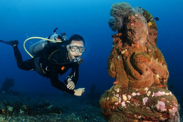 Scuba diving by statue at Coral Garden dive site in Tulamben, Bali